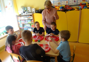 Dzieci formują kule z masy, pani Arletka przygląda się dzieciom.